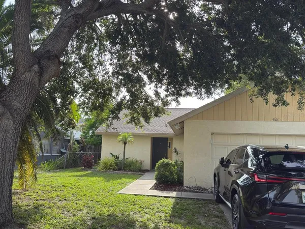a view of a house with backyard and a tree