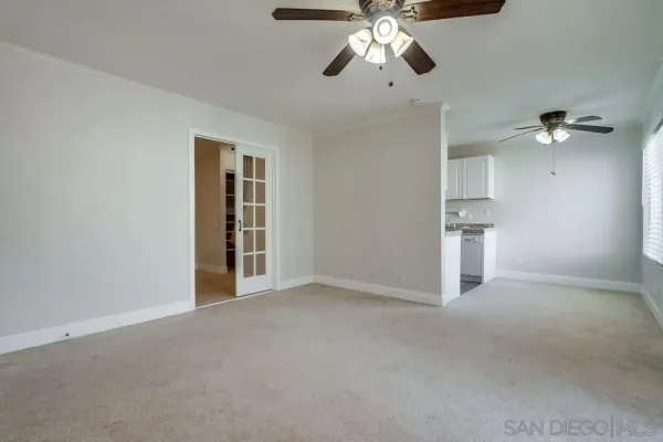 an empty room with a chandelier fan and windows
