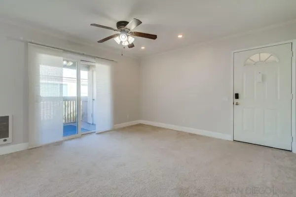an empty room with chandelier fan and windows