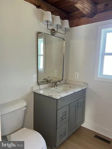 a bathroom with a granite countertop sink a toilet and a mirror