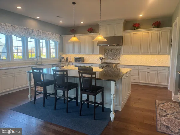 a kitchen with stainless steel appliances granite countertop a stove a refrigerator a kitchen island a dining table and chairs