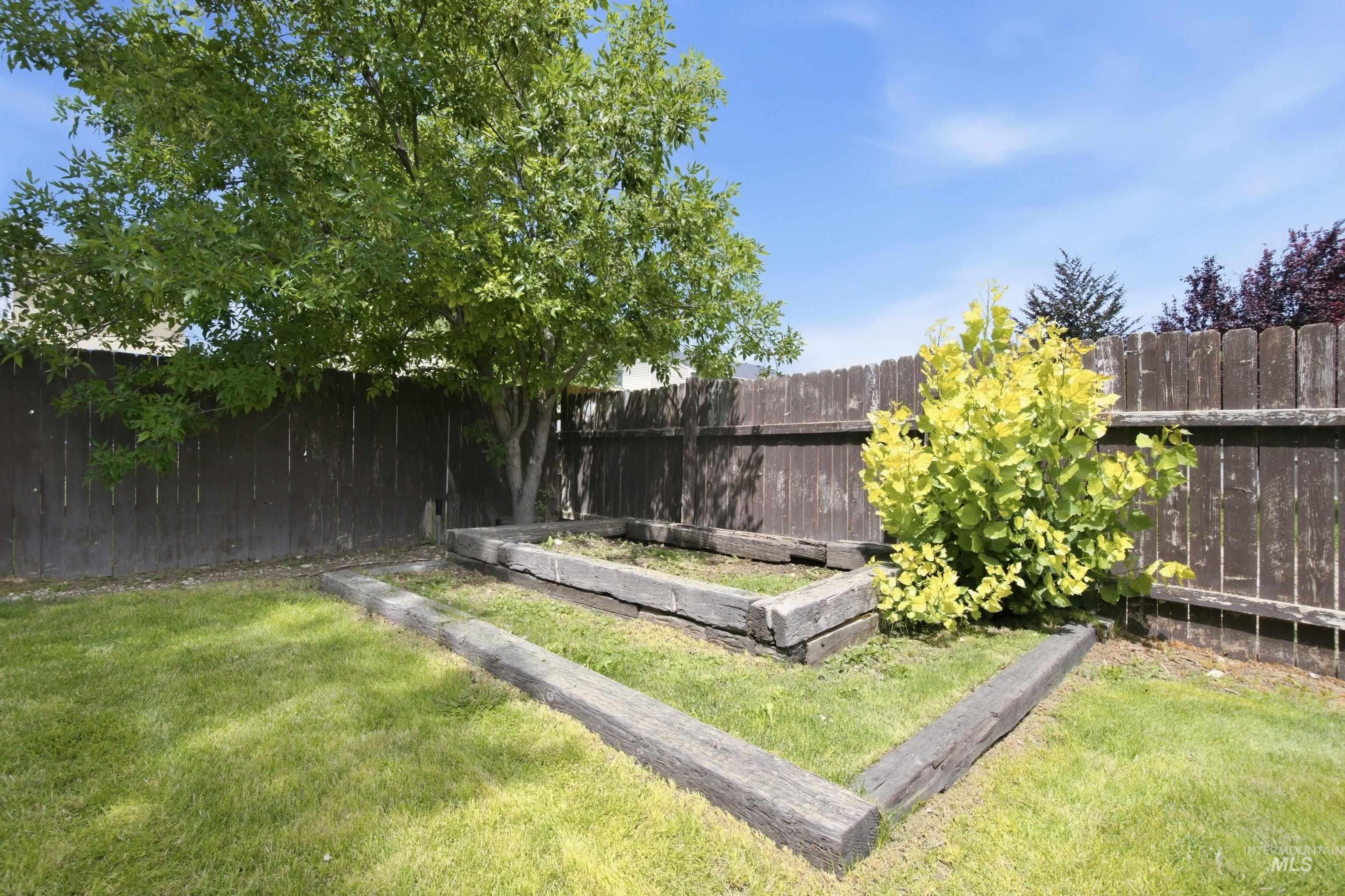 16759 Abram Avenue Caldwell, ID 83607 - Photo 29 of 33 Spacious backyard featuring a manicured lawn, established tree, and a corner garden bed framed by wood timbers