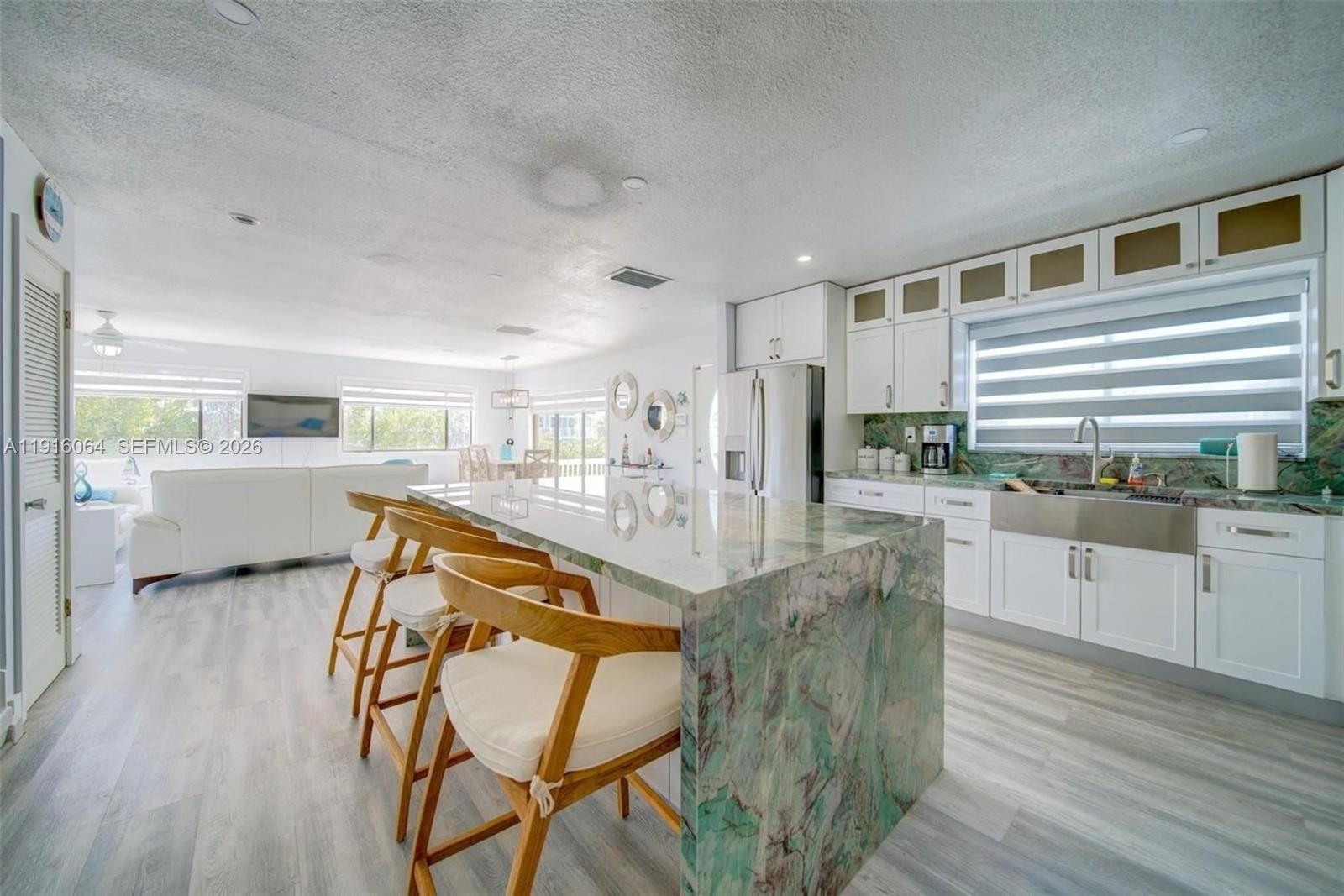 2 Snipe Road Key Largo, FL 33037 - Photo 14 of 45 a kitchen with stainless steel appliances kitchen island granite countertop a stove a refrigerator a dining table and chairs with wooden floor