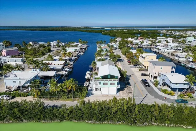 an aerial view of ocean and residential houses with outdoor space