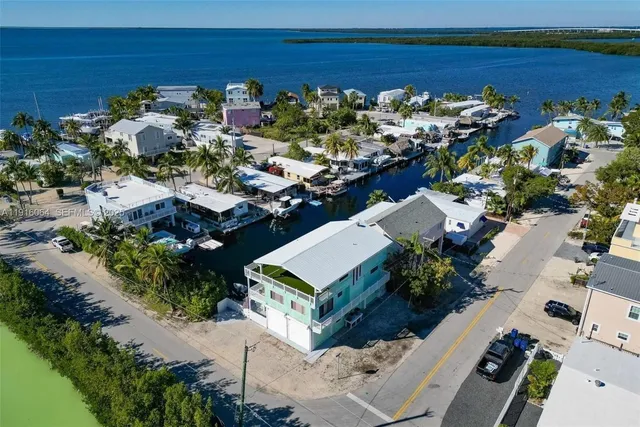 an aerial view of a city with lots of residential buildings ocean and mountain view in back