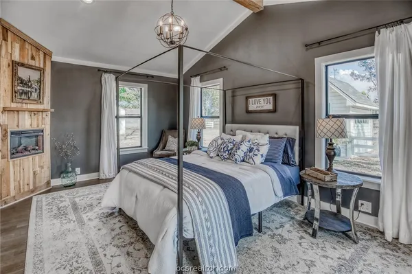 a bedroom with a bed large window with table and chair