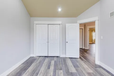 an empty room with wooden floor and a hallway