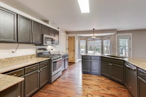 a large kitchen with granite countertop lots of counter top space and wooden floor