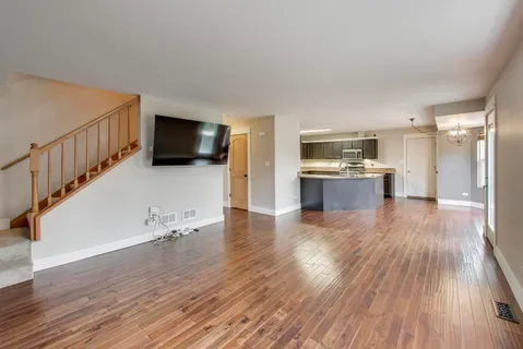 a view of a livingroom with wooden floor and a kitchen
