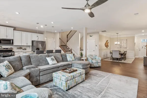 a living room with furniture kitchen view and a wooden floor
