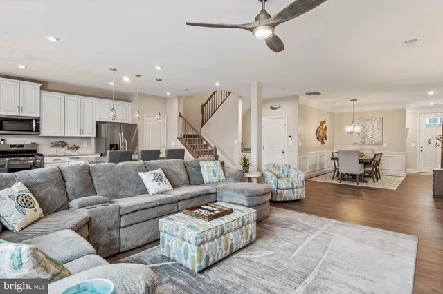 a living room with furniture kitchen view and a wooden floor
