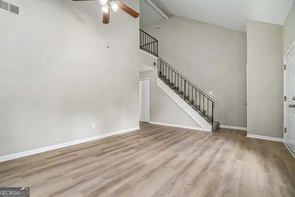 a view of an empty room with wooden floor and stairs