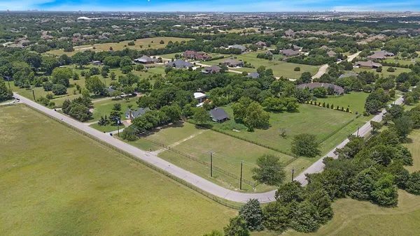 an aerial view of residential houses with outdoor space and trees