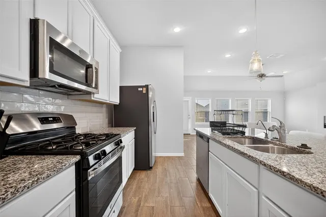 a kitchen with stainless steel appliances kitchen island granite countertop a stove sink microwave and refrigerator
