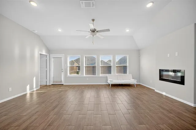 a view of a livingroom with wooden floor a ceiling fan and windows