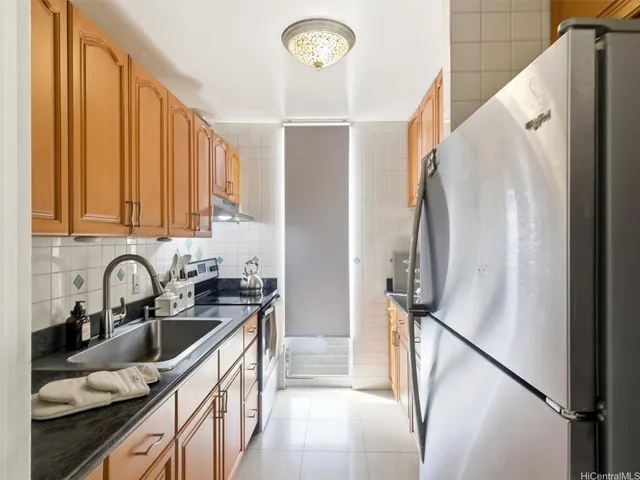 a kitchen with stainless steel appliances a sink a refrigerator a counter space and a window