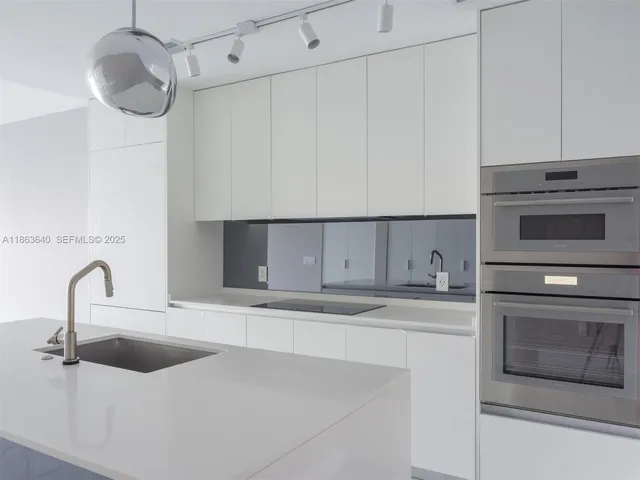 a kitchen with stainless steel appliances a sink a stove top oven a counter space and cabinets