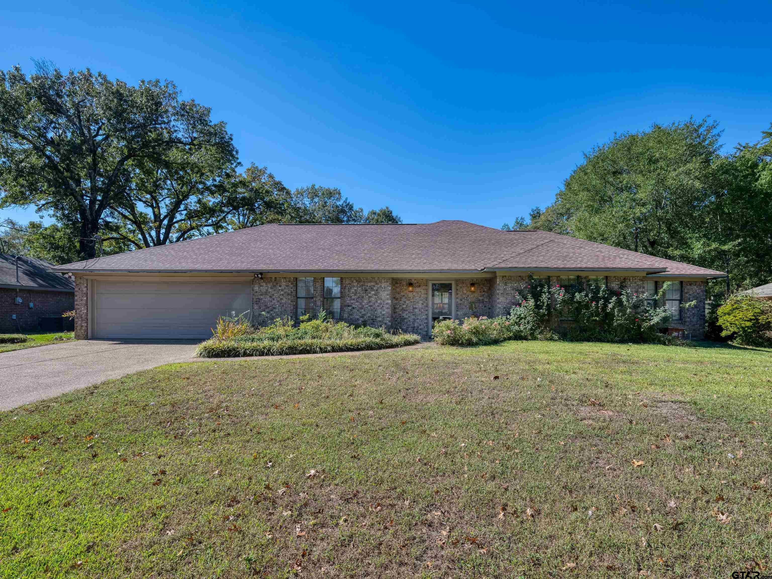 a view of a house with a yard and large tree