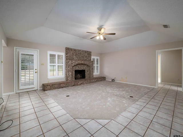 a view of an empty room with window and chandelier fan