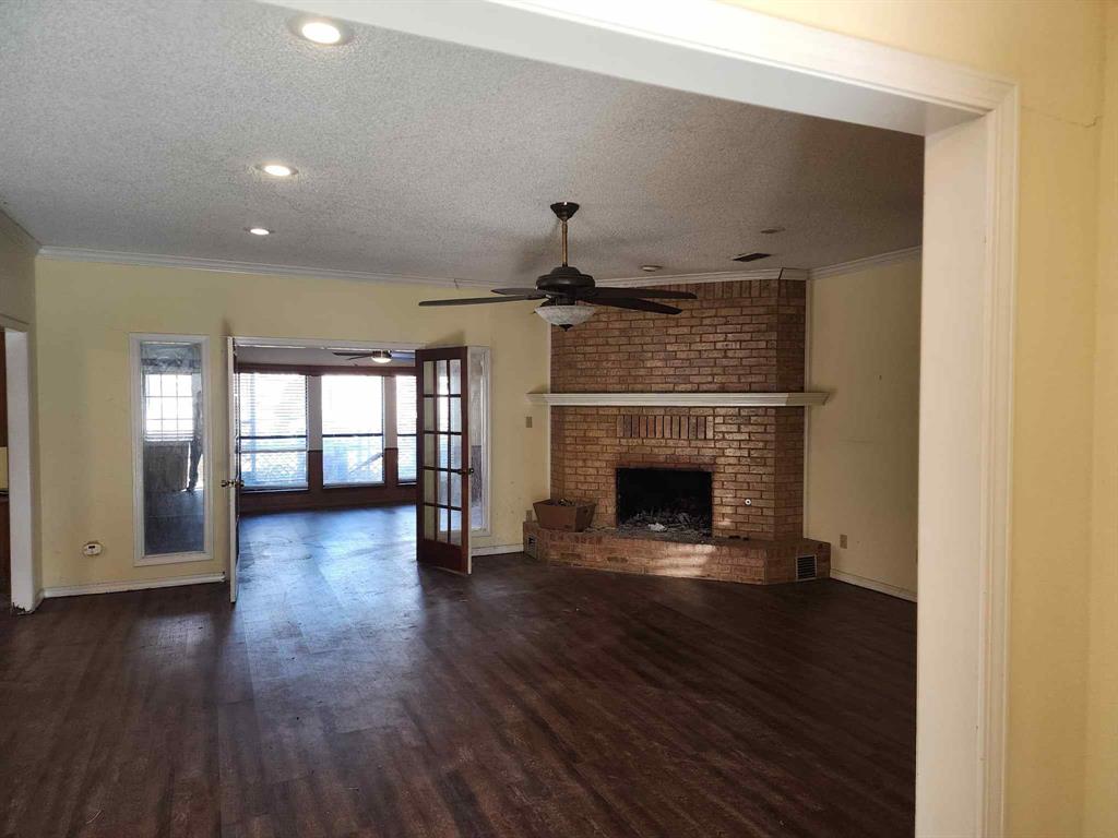 1316 Edna Street Commerce, TX 75428 - Photo 3 of 16 a view of an empty room with wooden floor fireplace and a window
