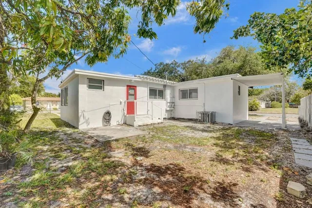 a view of a white house with a yard and large tree