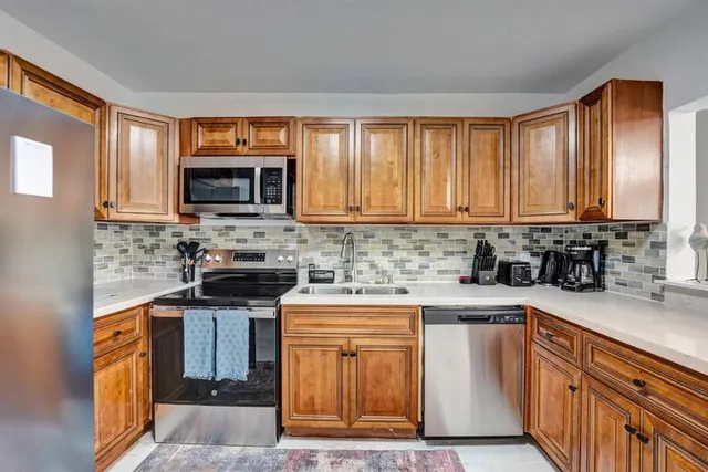 a kitchen with stainless steel appliances granite countertop a stove a sink dishwasher and a microwave oven with cabinets
