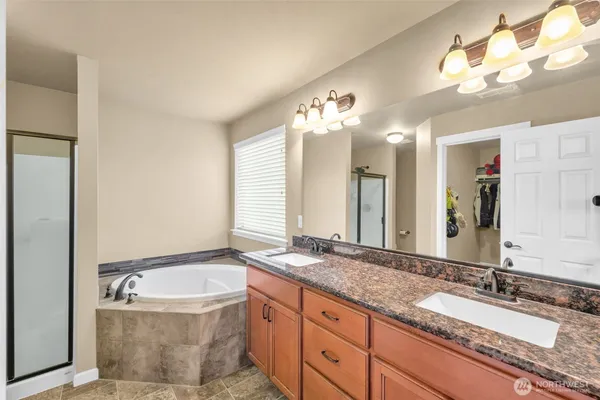 a bathroom with a granite countertop bathtub a double vanity sink and a mirror