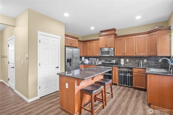 a kitchen with stainless steel appliances granite countertop a refrigerator a sink dishwasher a stove and white countertops with wooden floor