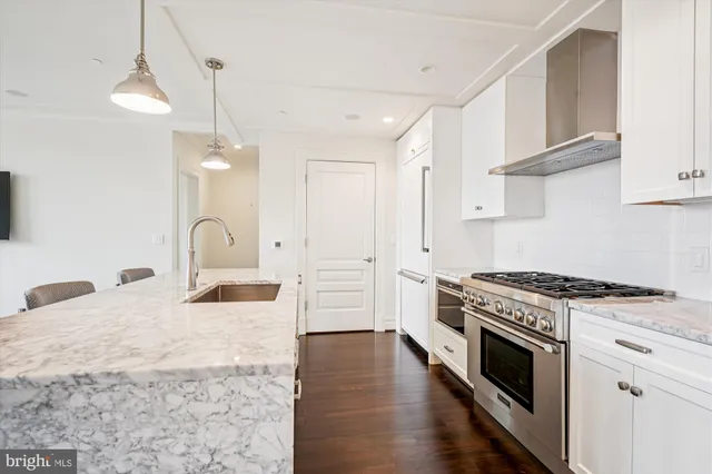 a kitchen with stainless steel appliances granite countertop a stove a sink and white cabinets