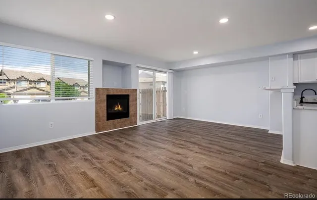 an empty room with wooden floor fireplace and windows