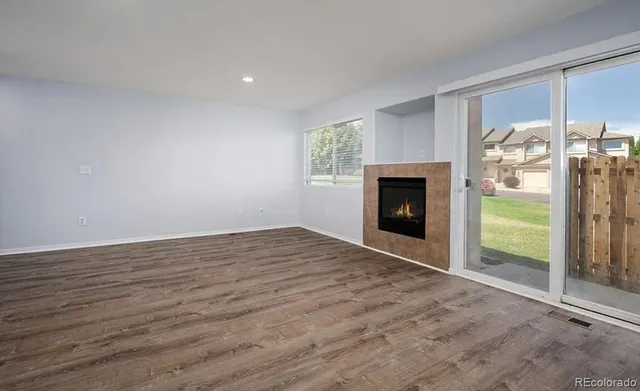 a view of empty room with wooden floor and fireplace