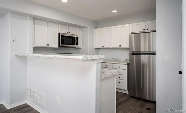 a kitchen with stainless steel appliances white cabinets and a refrigerator