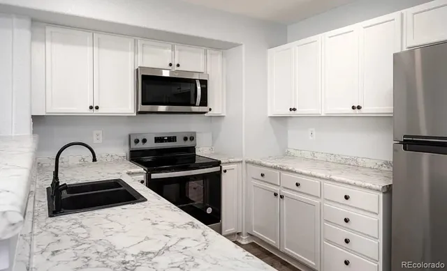 a kitchen with granite countertop white cabinets and stainless steel appliances