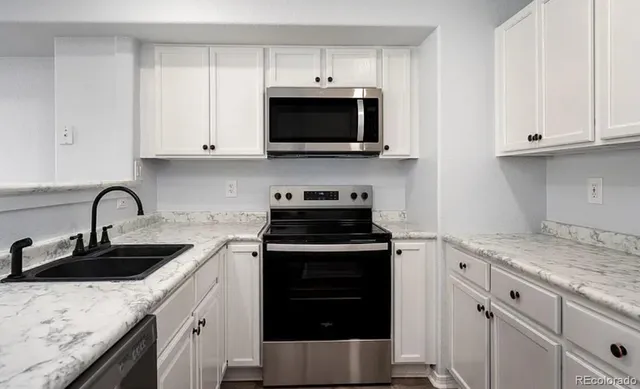 a kitchen with granite countertop white cabinets and stainless steel appliances