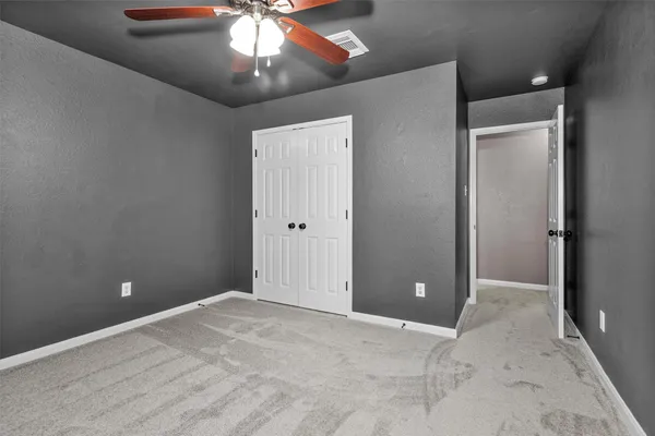 an empty room with windows and fan