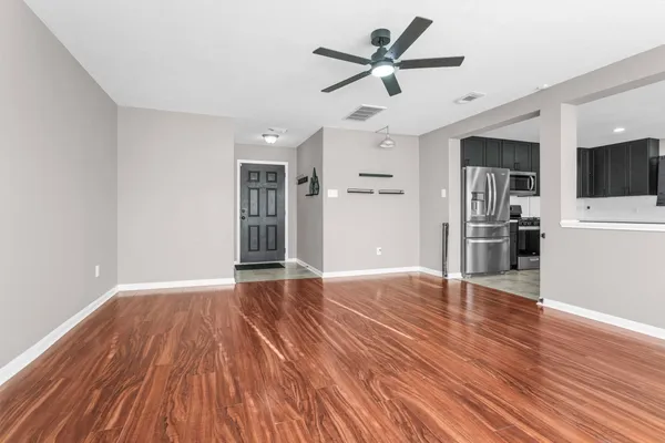 a view of an empty room with wooden floor and a window