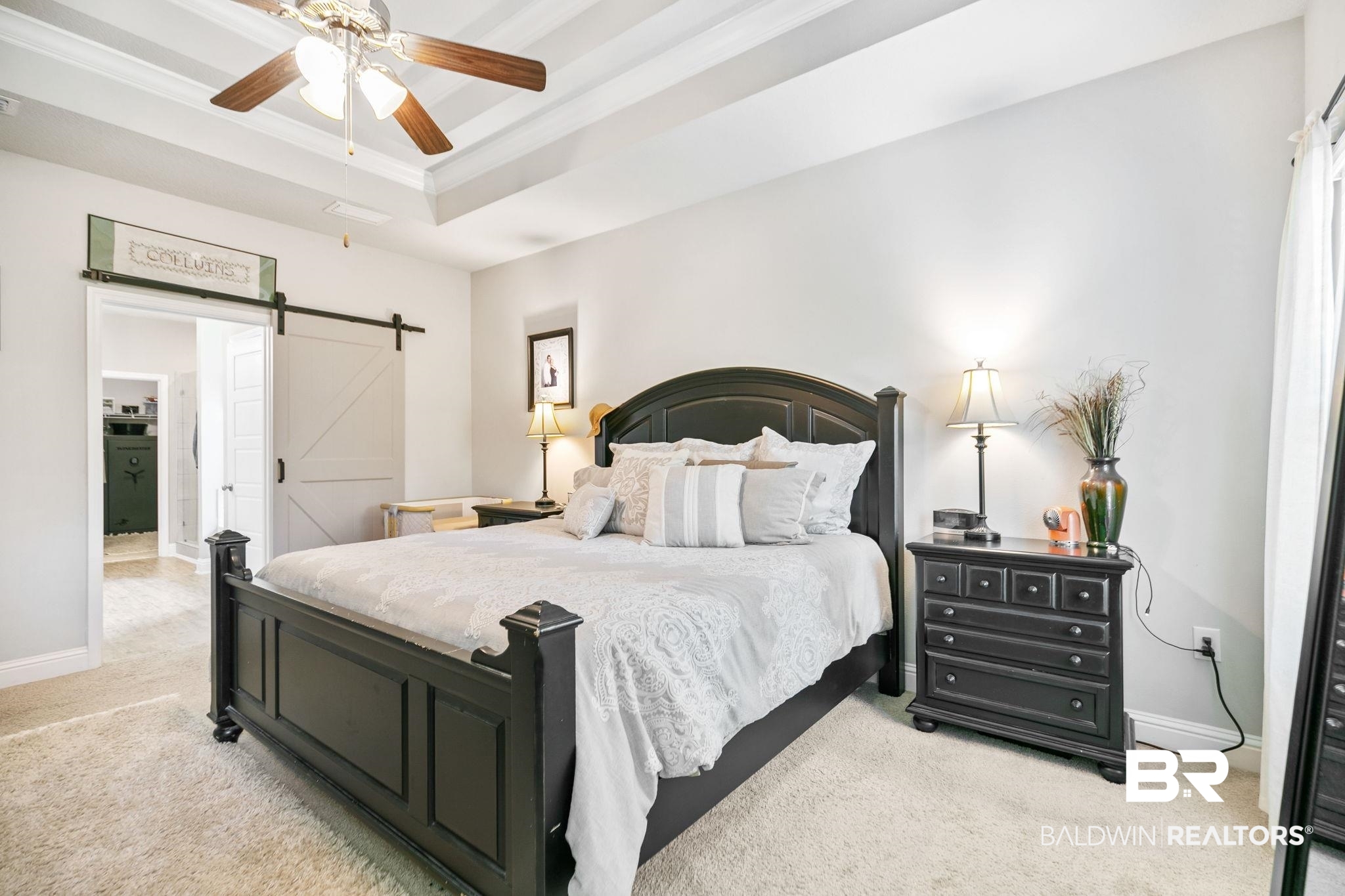 31402 Hoot Owl Road Daphne, AL 36527 - Photo 14 of 43 Bedroom with ceiling fan, a tray ceiling, a barn door, and light colored carpet