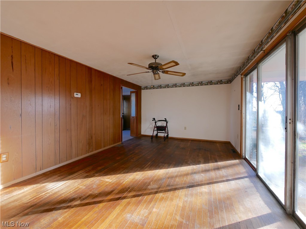 61784 Ray Ramsey Road Shadyside, OH 43947 - Photo 16 of 29 Empty room featuring plenty of natural light, dark wood-type flooring, wood walls, and ceiling fan
