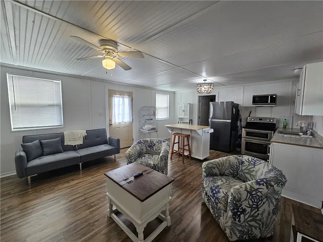 a living room with furniture kitchen view and a wooden floor