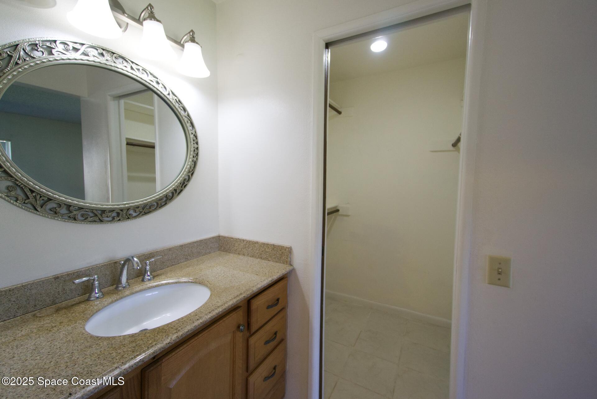 1980 Talloak Road Melbourne, FL 32935 - Photo 7 of 13 a bathroom with a granite countertop sink and a mirror