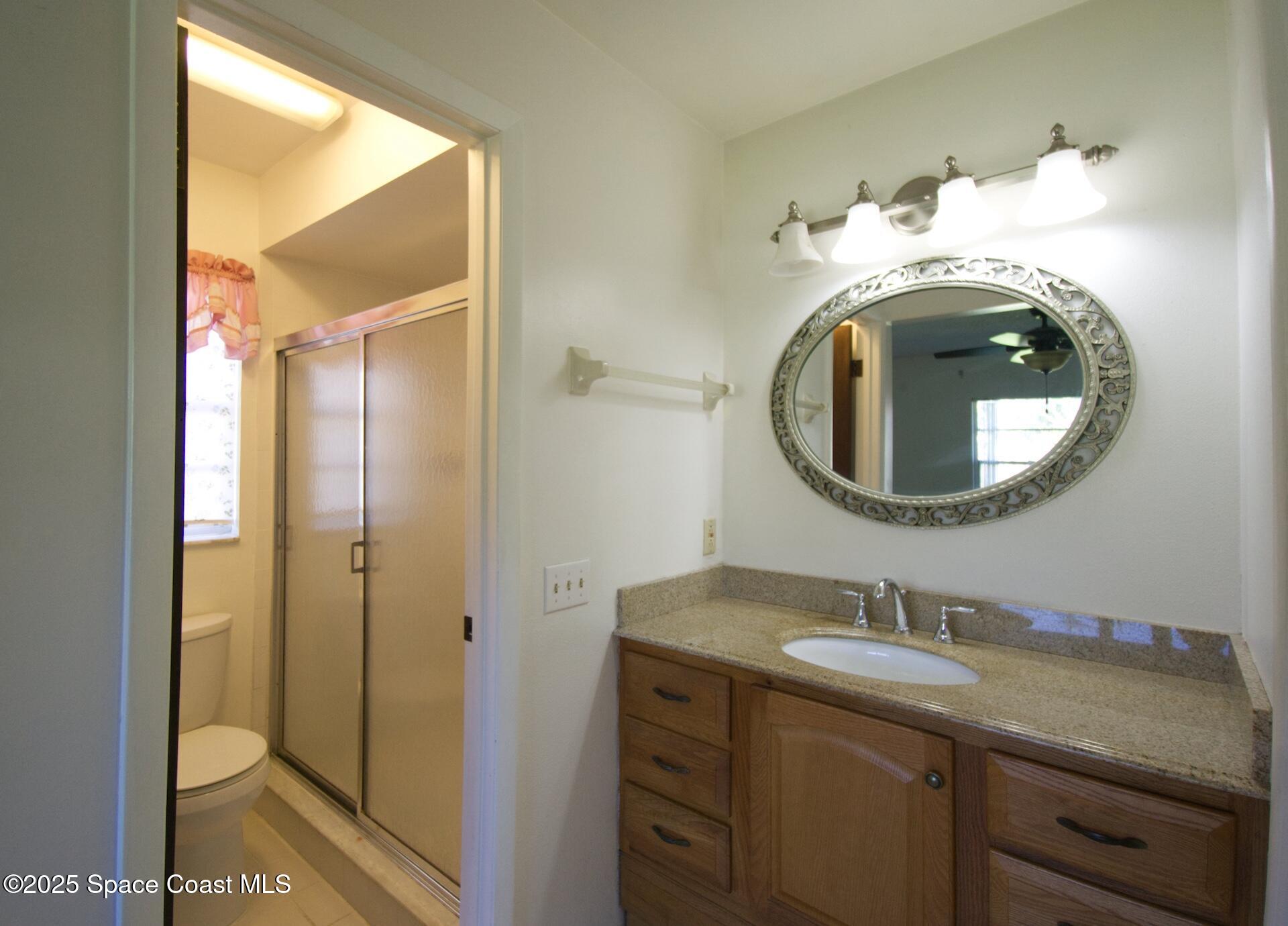 1980 Talloak Road Melbourne, FL 32935 - Photo 8 of 13 a bathroom with a granite countertop toilet sink and mirror