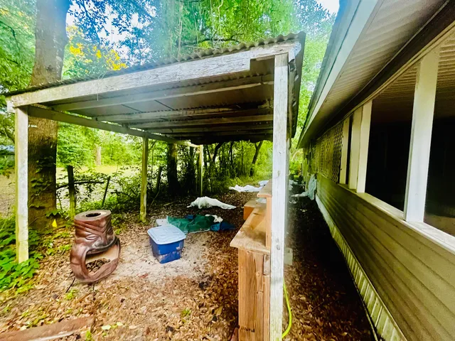 a view of a patio with table and chairs potted plants with floor to ceiling window and wooden fence