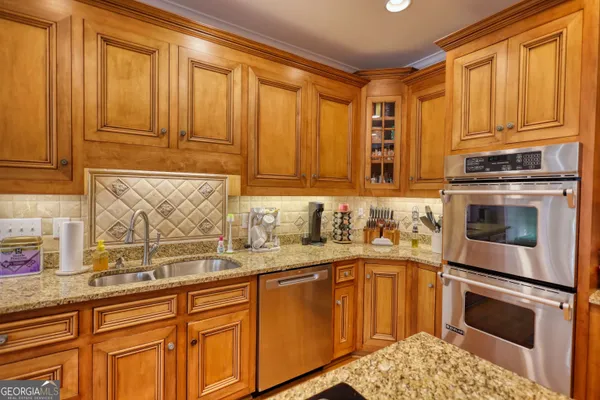 a kitchen with stainless steel appliances granite countertop a refrigerator a stove top oven a dining table and chairs with wooden floor