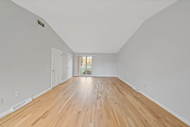 a view of empty room with window and wooden floor