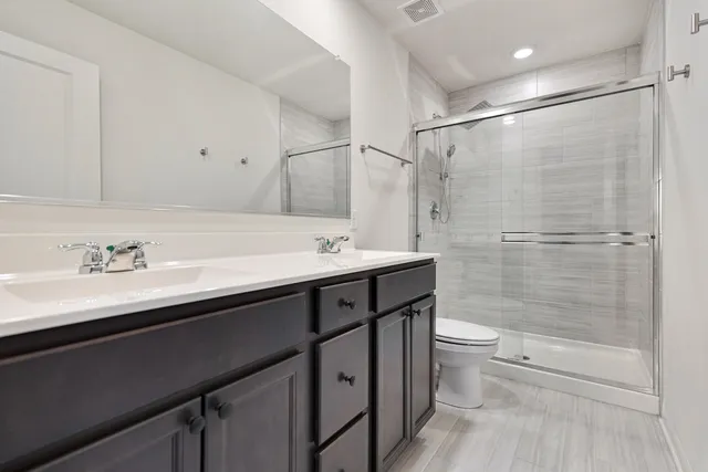 a bathroom with a double vanity sink toilet and shower