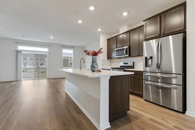 a kitchen with stainless steel appliances granite countertop a refrigerator a sink dishwasher a stove and a refrigerator with wooden floor