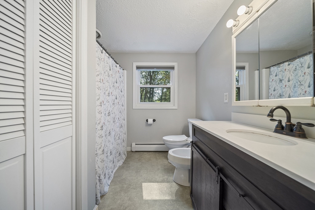 21 Woodman Road Amesbury, MA 01913 - Photo 17 of 30 a bathroom with a granite countertop sink toilet a mirror and shower
