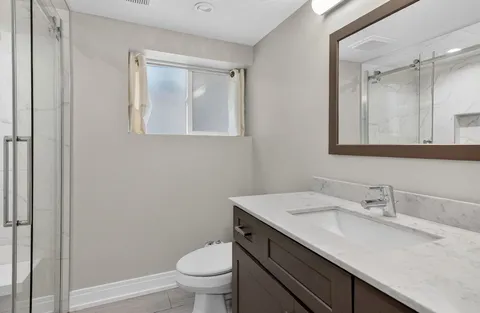 a bathroom with a granite countertop sink a toilet and a mirror