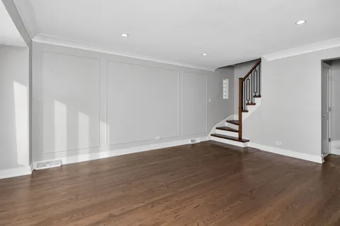a view of an empty room with wooden floor and stairs