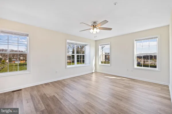 a view of empty room with wooden floor and fan